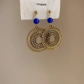 Détail de boucles d'oreilles bohèmes en disque doré ajouré avec perles bleu marine - Tige en argent-motif radial creux / Or