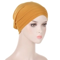 Close-up of mustard yellow pleated headwrap turban cap for women with elegant folds - Turmeric