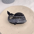 Detail of whale-shaped acetate hair claw clip with marble texture on ceramic tray - Black Round Whale