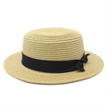 Detail of a brown woven boater hat featuring a flat top and black grosgrain ribbon bow - S (54-56cm) / Beige