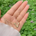 Polished 18K gold plated balloon bubble letter V pendant necklace held in hand - Gold V