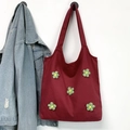 Borsa tote in tela bordeaux con decorazioni di fiori in lana verde su muro bianco - Borgogna