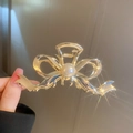 Molla per capelli dorata a fiocco con perla centrale tenuta in mano con cura - Fiocco d'Oro