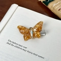 Pinza de mariposa ámbar de resina marmoleada con cristales sobre un libro antiguo - Pinza para el cabello / Naranja