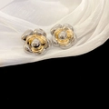 Macro shot of two-tone metal camellia flower stud earrings on white silk fabric background - Silver Flower Stud Earrings with Silver Pin