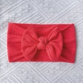 Detail of red cable knit baby headband with oversized bow on white lace background - Red