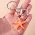 Close-up of orange starfish keychain with glitter resin detail and silver metal ring - Orange Starfish