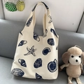 Detail of canvas tote bag featuring navy blue sea shell patterns on cream fabric - Shell