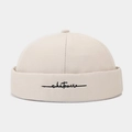 Close-up of beige cotton docker hat featuring black whatever cursive letter embroidery - Adjustable / Beige