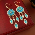 Detail von Vintage-Goldohrringen mit blauen Edelsteinen und Quasten auf Holzoberfläche - Blau