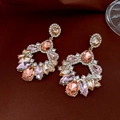Dettaglio di orecchini vintage con cristalli champagne e rosa su velluto elegante - Oro-Rosa