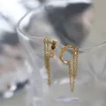 Makro-Detail von vergoldeten Titanstahl-Ohrclips mit Quastenkette und runden Scheiben - Gold