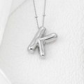 Macro shot of silver letter K pendant with high-polished mirror finish and fine bead chain - Letter K Pendant