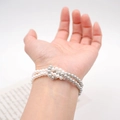 Elegante bracciale di perle con grani bianchi e grigio argento al polso di una donna - Bracciale / Bianco / Grigio