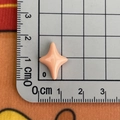 Détail d'un accessoire étoile en résine pêche sur une règle graduée pour voir la taille - Orange