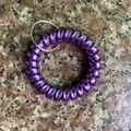 Macro shot of purple spiral telephone cord keychain with silver ring on marble - Metallic Dark Purple