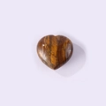 Polished tiger eye heart stone with natural brown and yellow stripes on purple background - Tiger's Eye