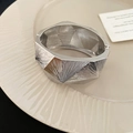 Dettaglio del bracciale rigido argento con linee radiali incise e chiusura laterale - Stile Spazzolato a Facette Geometriche / Argento