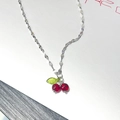 Collana a catena d'argento con un ciondolo a ciliegia rossa su sfondo minimalista - Argento