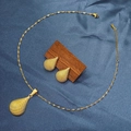 Detailed view of textured gold-tone teardrop necklace and earrings set on blue fabric - E6107-18/Gold Waterdrop Fine Texture