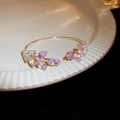 Vue macro d'un bracelet doré avec cristaux roses et blancs en forme de feuille sur céramique - Rose