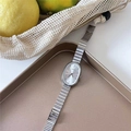 Detail view of oval silver quartz watch and chain bracelet set on golden tray - Single-Silver Case White Dial