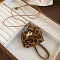 Détail d'un mini bijou de sac léopard avec fermoir doré dans un plateau à bijoux - Collier / Café Clair