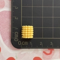 Detailed macro view of a 1cm yellow resin corn charm accessory on a scale board - Corn Segment