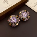 Detailed close-up of vintage baroque earrings with purple crystal and colorful rhinestones - Gold
