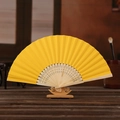 Vibrant yellow 6-inch DIY folding paper fan with carved bamboo ribs on wooden stand - Gold Yellow