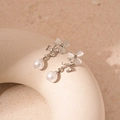Vista de detalle de pendientes de flores con pétalos de ojo de gato y perlas en base beige - Colgante de Perla de Flor Plateada (Pin de Plata)