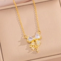 Collana con fiocco dorato e pendente in zircone esposta in un portagioie beige - Collana Fiocco Oro Bianco (8844)
