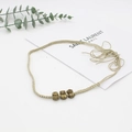 Detail of woven beige hat band with vintage bronze floral metal beads on white background - Handmade Three Beads Braided Jewelry Style (12)