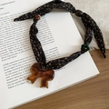 Dettaglio della collana con fiocco in tessuto e ciondolo a fiore in resina su libro - Stile Pendente a Fiocco / Viola Scuro-Caffè