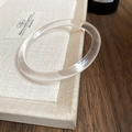 Close-up of minimalist transparent acrylic resin bangle with smooth polished finish - Clear