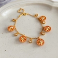 Detail van een vergulde armband met ster- en cirkelhangers op een wit bordje - Armband - Goud - Roze (Stijl 1)