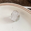 Detail van zilveren ring met grote witte harssteen op een wit keramisch bordje - Onregelmatige Ovale Ring - Zilver & Wit (HR2793)