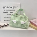 Close-up of a light green polka dot canvas bag with 3D plush wings and top handles - Green