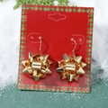 Macro view of gold bow earrings on a red display card with festive Christmas decor - 03 Gold Gift Flower Ball