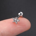 Macro shot of a tiny silver star cartilage stud with cubic zirconia on a fingertip - Star Silver - 1PC