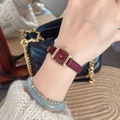 Close-up of a women's square gold watch with a textured red leather strap on a wrist - Small Square Watch