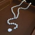 Detalle de cierre de hoja con circón y colgante de perla de gota en un collar largo elegante - Blanco