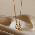 Dettaglio del ciondolo a cuore in acciaio dorato 18K con perla su sfondo di seta - Arco di Perle con Sfera Lucida