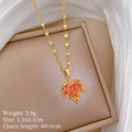 Close-up of golden maple leaf pendant with orange gemstone on beige jewelry box - Red Maple Leaf Necklace (E131)