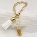 Detail of cross-shaped resin keychain with white stones, gold foil, and a soft white tassel - White (White Stone Gold Foil Cross + White Tassel)