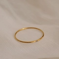 Close-up of minimalist thin gold titanium ring with a tiny sparkling zircon gemstone - US 7 / Single Stone / Gold