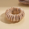 Dettaglio ravvicinato di un bracciale geometrico in acrilico con perle effetto marmo - Motivo Marmo Bianco Sporco