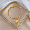 Dettaglio del bracciale a sfere dorate con ciondolo a coniglio in occhio di gatto - Oro