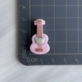 Rosa Gitarren-Accessoire aus Harz mit 3 cm Größenangabe auf einer Schneidematte - Bär Gitarre