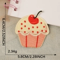 Embroidered pink cupcake patch with red cherry on denim and notebook background - Yellow Red Cherry